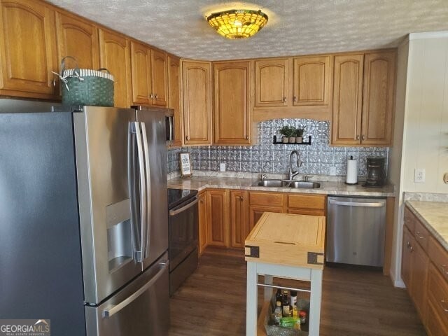 kitchen featuring sink, appliances with stainless steel finishes, dark hardwood / wood-style floors, a textured ceiling, and decorative backsplash