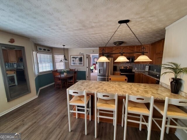 kitchen featuring appliances with stainless steel finishes, dark hardwood / wood-style floors, decorative light fixtures, tasteful backsplash, and kitchen peninsula