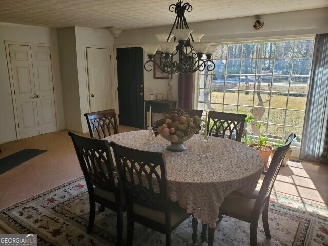 dining space with carpet, a notable chandelier, and a textured ceiling