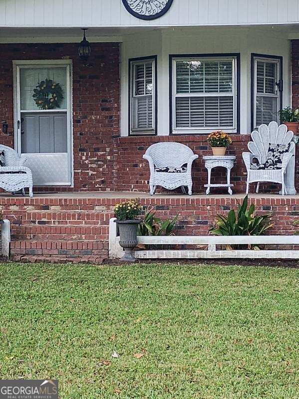 view of exterior entry featuring a lawn and covered porch