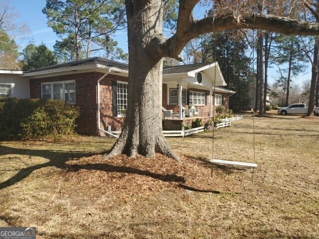 exterior space featuring covered porch and a front lawn