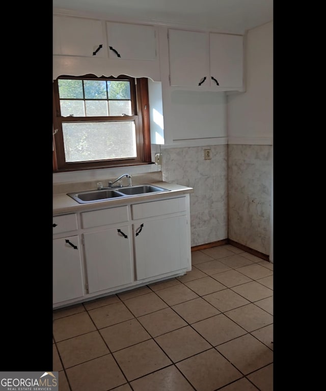 kitchen with sink, light tile patterned floors, and white cabinets