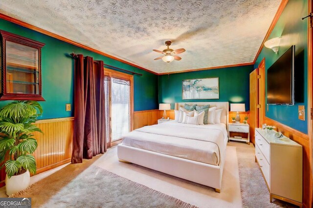 carpeted bedroom featuring ceiling fan, crown molding, wooden walls, and a textured ceiling