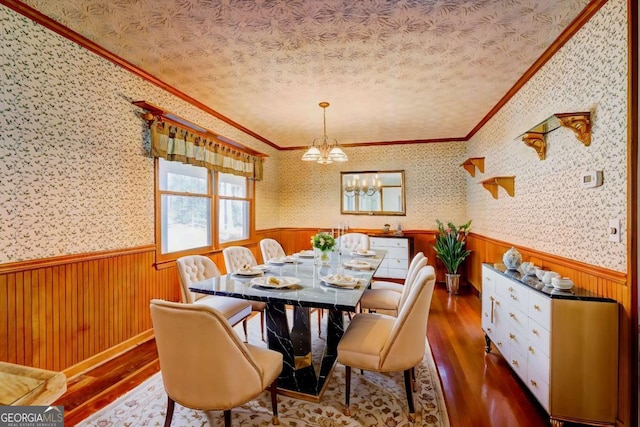 dining area featuring dark wood-type flooring, ornamental molding, a textured ceiling, and a notable chandelier