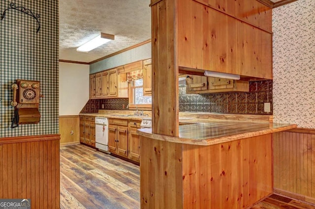 kitchen with sink, a textured ceiling, ornamental molding, white dishwasher, and hardwood / wood-style floors