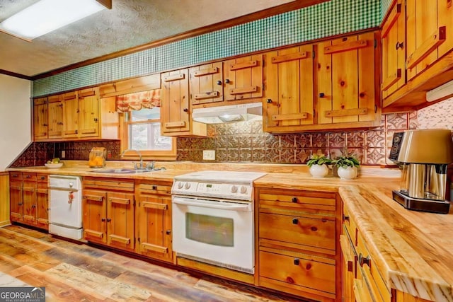 kitchen with sink, white appliances, light hardwood / wood-style floors, wood counters, and decorative backsplash