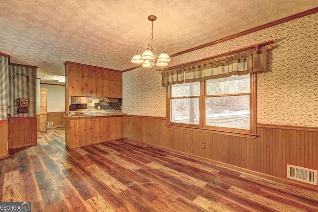 kitchen with dark hardwood / wood-style floors, decorative light fixtures, kitchen peninsula, and a textured ceiling