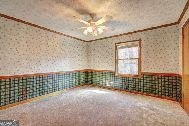 carpeted spare room with ornamental molding, ceiling fan, and a textured ceiling