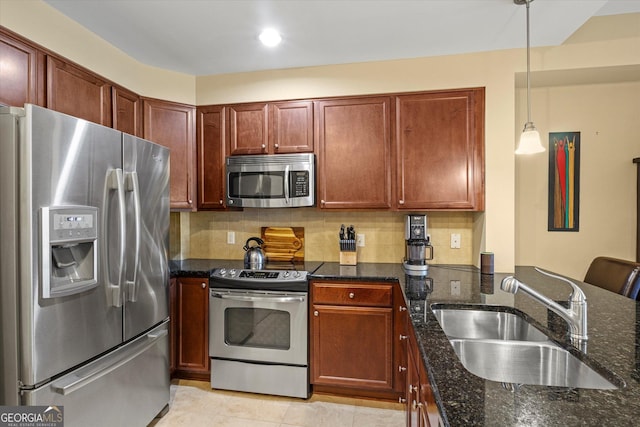 kitchen with appliances with stainless steel finishes, tasteful backsplash, sink, dark stone counters, and hanging light fixtures