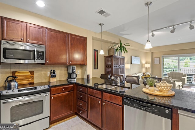 kitchen featuring pendant lighting, sink, dark stone countertops, stainless steel appliances, and decorative backsplash