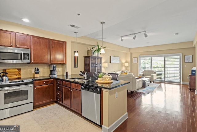 kitchen with sink, appliances with stainless steel finishes, backsplash, decorative light fixtures, and kitchen peninsula