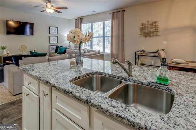 kitchen featuring sink, white cabinetry, dark hardwood / wood-style flooring, ceiling fan, and light stone countertops