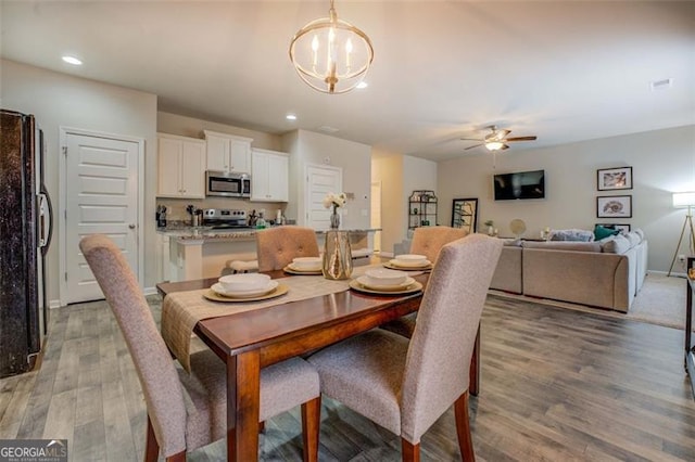 dining room featuring ceiling fan with notable chandelier and hardwood / wood-style floors