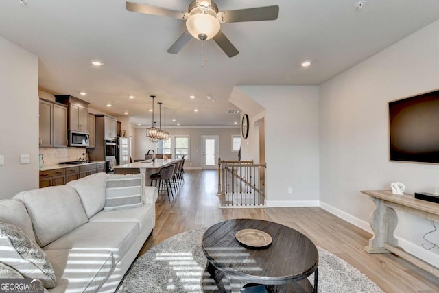 living room featuring ceiling fan, sink, and light hardwood / wood-style floors