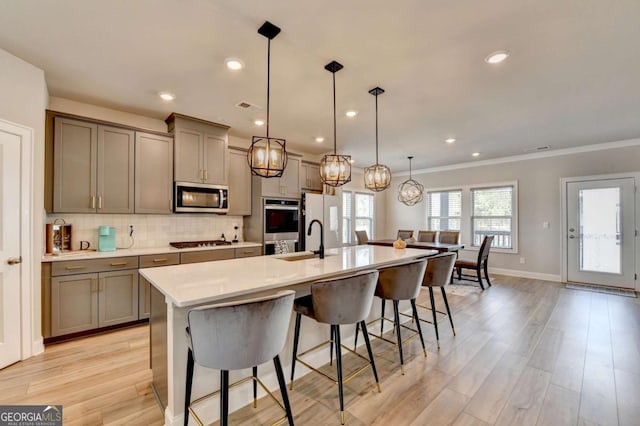 kitchen with pendant lighting, stainless steel appliances, a breakfast bar, and an island with sink