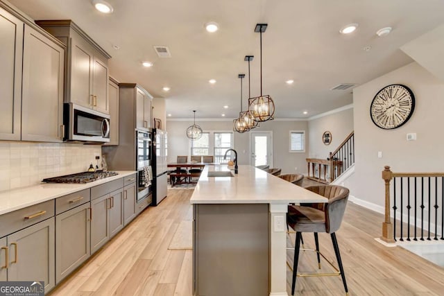 kitchen featuring pendant lighting, sink, a breakfast bar, stainless steel appliances, and an island with sink