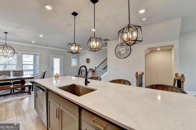 kitchen featuring dishwasher, sink, a chandelier, hanging light fixtures, and light hardwood / wood-style flooring