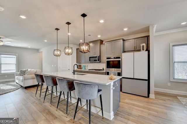 kitchen featuring pendant lighting, a breakfast bar area, appliances with stainless steel finishes, a healthy amount of sunlight, and a center island with sink