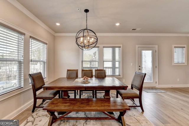 dining area with crown molding, plenty of natural light, a chandelier, and light wood-type flooring