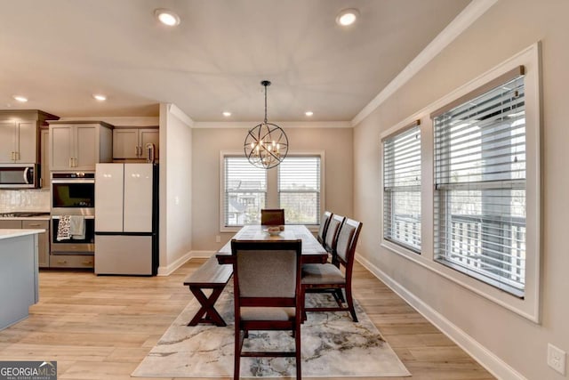 dining area with ornamental molding, a chandelier, and light hardwood / wood-style floors