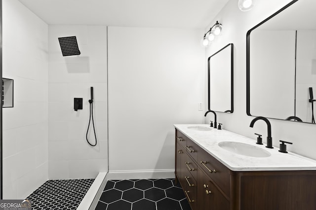 bathroom with double vanity, tiled shower, and a sink