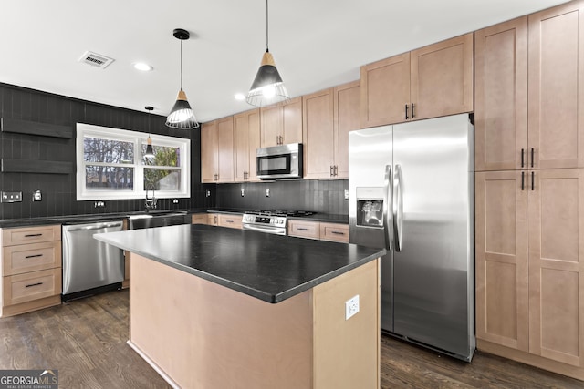 kitchen with appliances with stainless steel finishes, dark hardwood / wood-style flooring, a center island, and hanging light fixtures