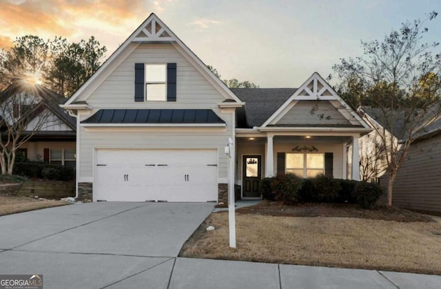 view of front of home featuring a garage, driveway, a standing seam roof, stone siding, and metal roof