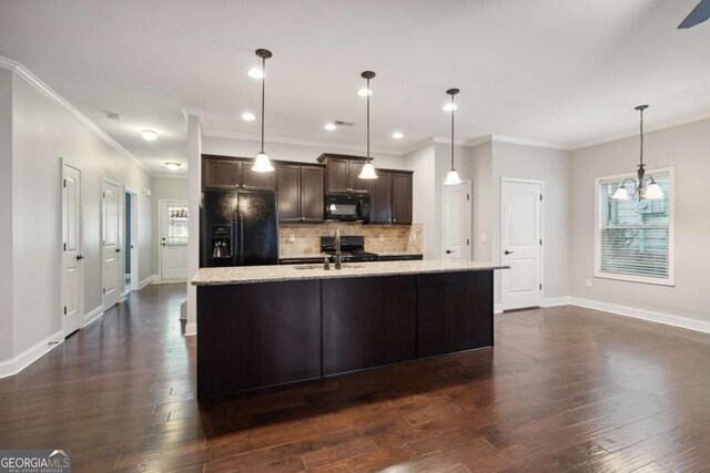 kitchen featuring a kitchen island with sink, dark brown cabinets, black appliances, decorative backsplash, and decorative light fixtures