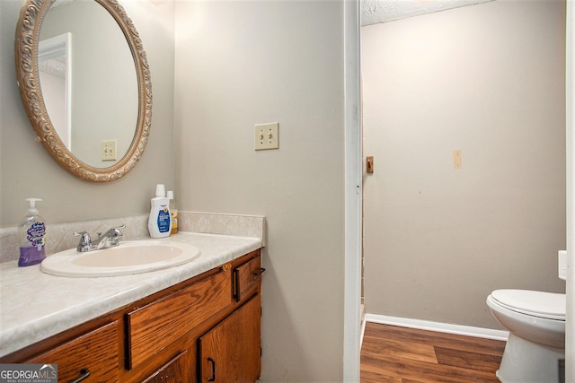 bathroom with wood-type flooring, vanity, and toilet