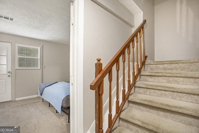 stairway featuring carpet floors and a textured ceiling