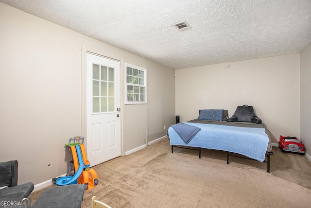 bedroom with light carpet and a textured ceiling