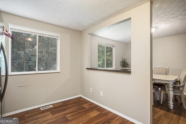 empty room featuring dark wood-type flooring and a textured ceiling