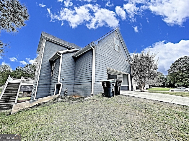 view of side of home with driveway, an attached garage, and stairs