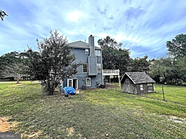 back of property with a yard, a deck, and a shed