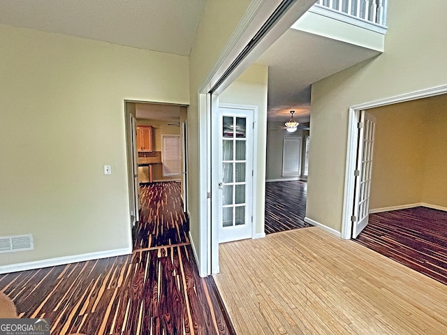 hallway with wood finished floors, visible vents, and baseboards