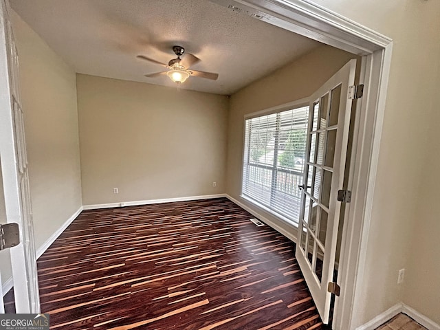 unfurnished room with dark wood-style floors, a textured ceiling, a ceiling fan, and baseboards