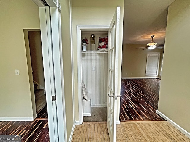 corridor featuring stairs, baseboards, and wood finished floors