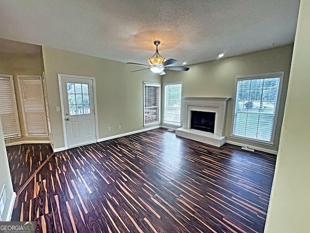 unfurnished living room featuring plenty of natural light, dark hardwood / wood-style floors, and ceiling fan