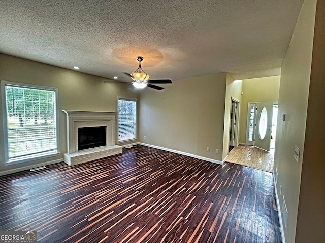 unfurnished living room featuring ceiling fan, dark wood-type flooring, and a textured ceiling