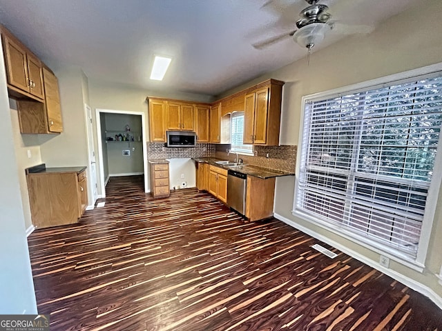 kitchen with tasteful backsplash, dark countertops, dark wood-style floors, appliances with stainless steel finishes, and a sink