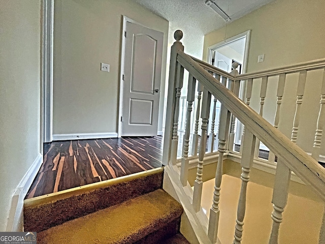 stairway with wood finished floors, attic access, and baseboards