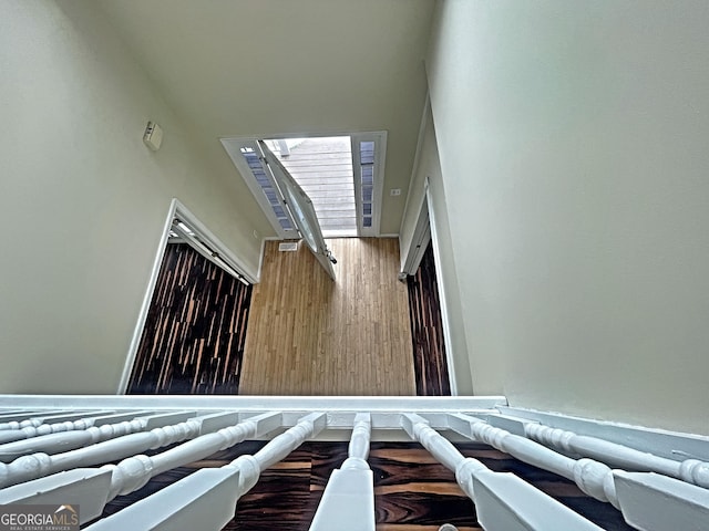 stairs featuring a towering ceiling and wood finished floors