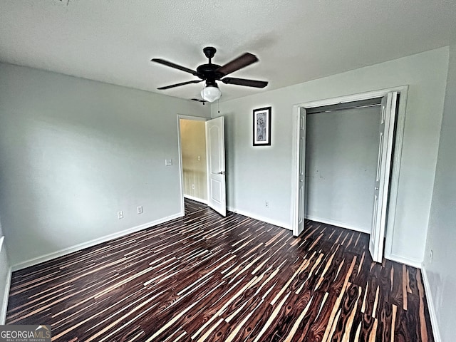 unfurnished bedroom featuring dark wood-style flooring, a closet, ceiling fan, a textured ceiling, and baseboards