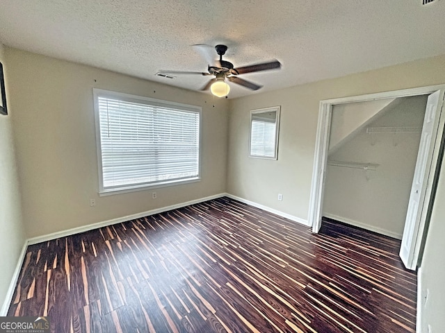 unfurnished bedroom featuring a closet, visible vents, dark wood-type flooring, a textured ceiling, and baseboards