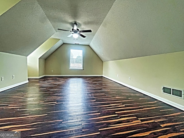 bonus room featuring ceiling fan, dark hardwood / wood-style floors, vaulted ceiling, and a textured ceiling