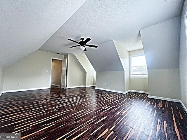 bonus room with vaulted ceiling, a textured ceiling, dark wood finished floors, and baseboards