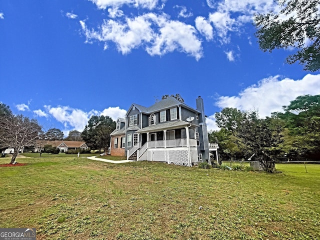 view of front of home with covered porch, stairs, a chimney, and a front lawn