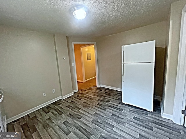 spare room featuring dark wood-type flooring, a textured ceiling, and baseboards