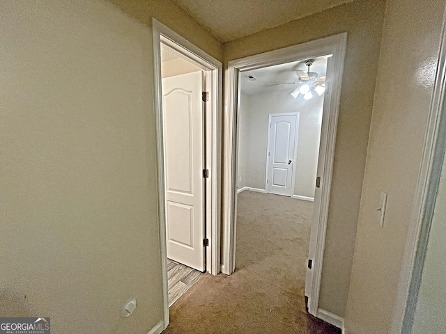 corridor with baseboards and light colored carpet