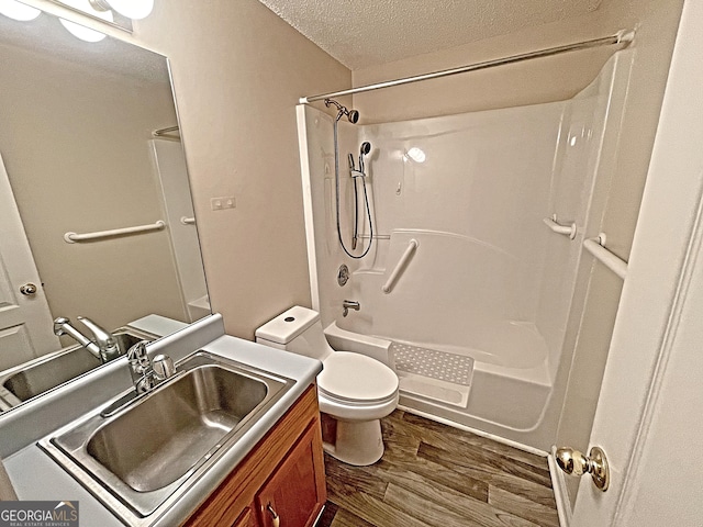 full bathroom featuring toilet,  shower combination, a textured ceiling, vanity, and hardwood / wood-style floors